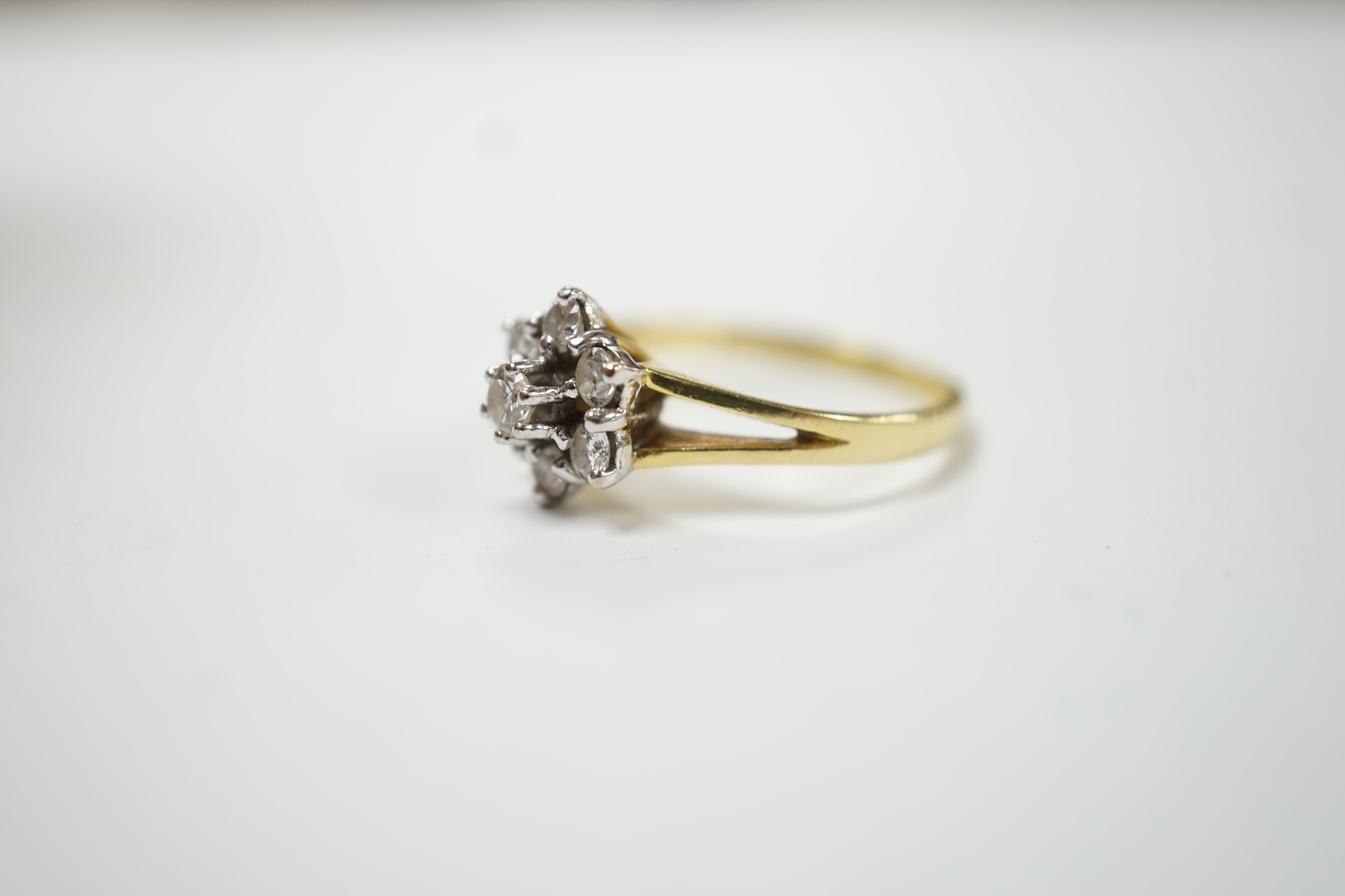 A modern 18ct gold and seven stone diamond set flower head cluster ring, size M, gross weight 3.2 grams. Fair condition.